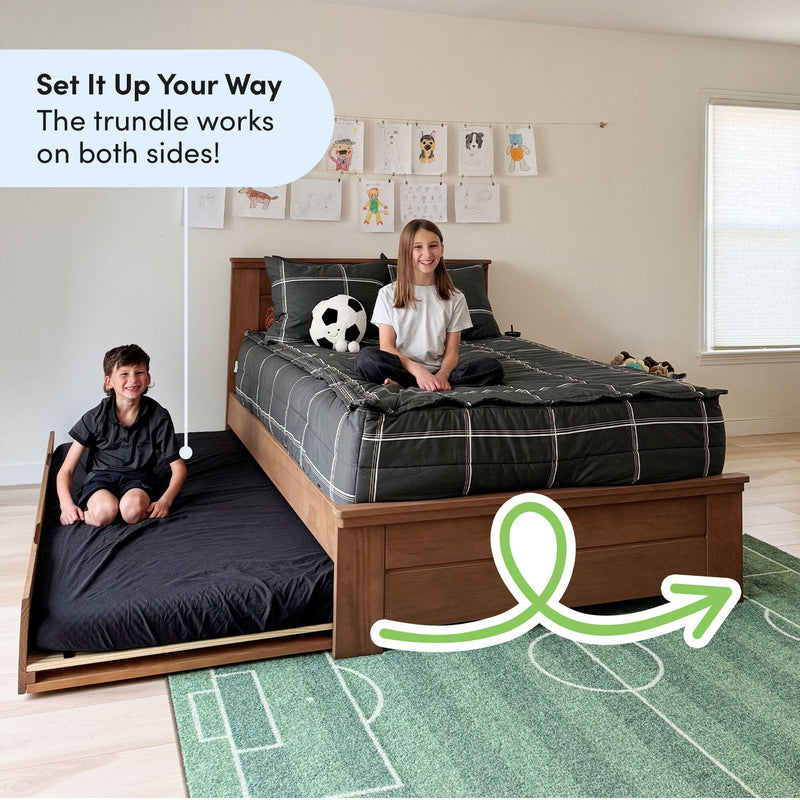 Pull-out trundle bed for kids in bright bedroom — wooden platform bed with gray plaid bedding, soccer plush, green soccer rug and wall art
