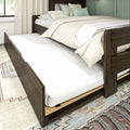 Wooden twin trundle bed with beige bedding and pastel green decorative pillows in a modern bedroom — space-saving under-bed pull-out mattress