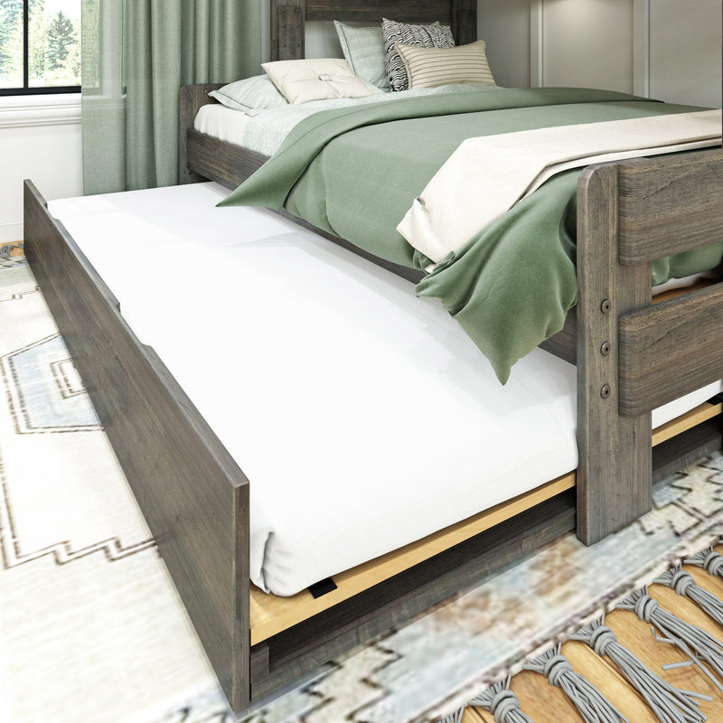 Rustic wooden trundle bed with green bedding and decorative pillows, white mattress and storage drawer in a cozy farmhouse bedroom with natural light