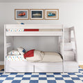 White wooden bunk bed with children's car-print bedding, red throw and pillows, three framed vintage car prints above in a bright boys' bedroom with blue check rug