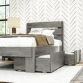 Gray wood platform bed with under-bed trundle and storage drawers, white bedding and beige throw, bedside lamp and chevron wallpaper in a modern farmhouse bedroom with natural light