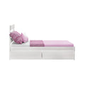 White wooden twin bed with pink fitted sheet, textured pink throw and pillows and built-in under-bed storage drawers