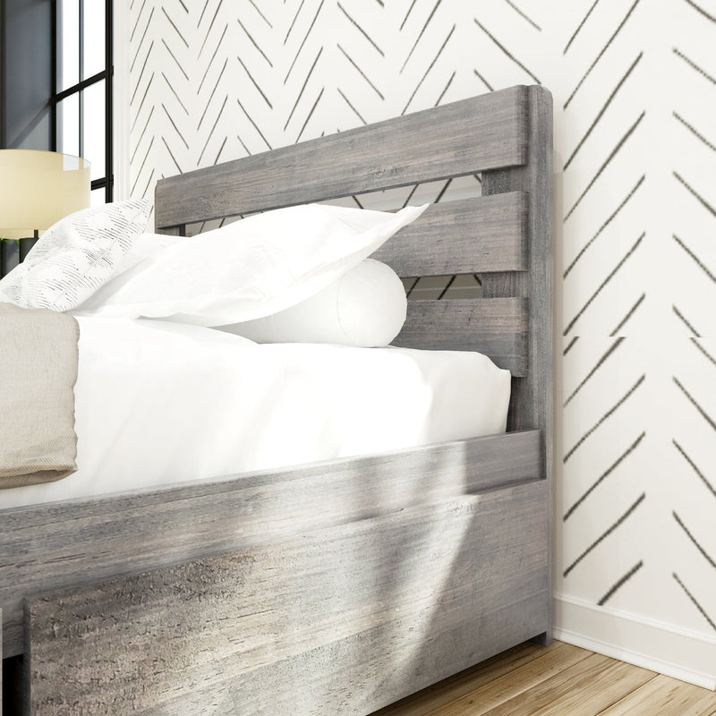 Gray wooden slatted bed frame with white bedding, chevron wallpaper, bedside lamp and hardwood floor in modern farmhouse bedroom