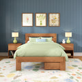 Modern bedroom interior featuring a wooden platform bed with light-green bedding, blue shiplap wall, three framed floral prints, matching bedside lamps and a floral area rug