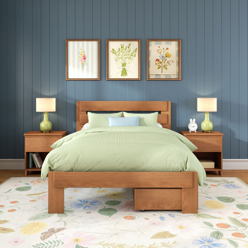 Modern bedroom interior featuring a wooden platform bed with light-green bedding, blue shiplap wall, three framed floral prints, matching bedside lamps and a floral area rug