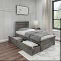 Gray wooden twin storage bed with under-bed pull-out drawers, gray bedding and nightstand lamp in a neutral modern farmhouse bedroom