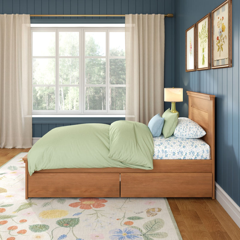 Cozy bedroom interior with wooden storage bed, light green bedding and floral sheets, blue shiplap wall, large window with sheer curtains and floral rug