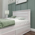 Modern bedroom with whitewashed wooden bed frame, green board-and-batten accent wall, coordinated green bedding and bedside lamp