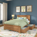 Bedroom with wooden storage bed and under-bed drawers, sage green bedding, blue paneled accent wall and floral framed art