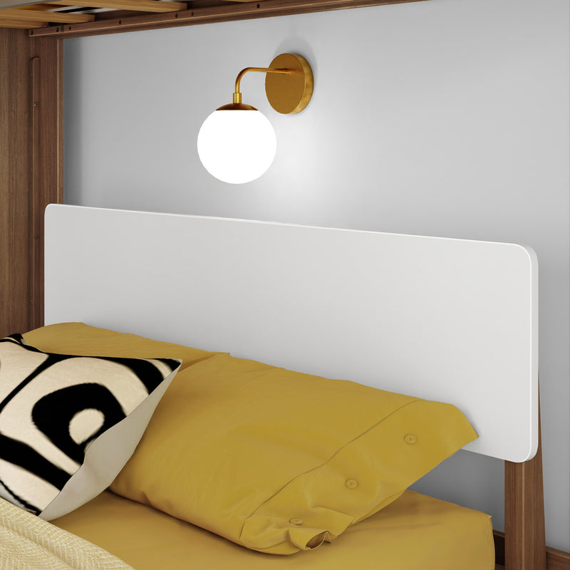 Modern brass globe wall sconce above bed with yellow bedding and black-and-white accent pillow on wooden bed frame, bedroom wall lighting