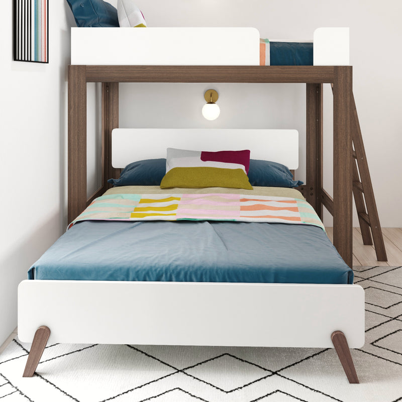 Modern wooden bunk bed with white panels, colorful pillows and quilt, side ladder and wall sconce in contemporary kids' bedroom