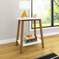 Mid-century modern wooden side table with white top and lower shelf holding books and a yellow cone table lamp beside a large window in a bright living room