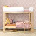 Wooden loft bunk bed with ladder in pink pastel nursery, styled with blush bedding, yellow accent pillows and a gray stuffed bunny.