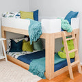 Kids wooden bunk bed with dinosaur bedding, teal throw blanket, blue and green pillows and plush dinosaur toy, children's bedroom decor