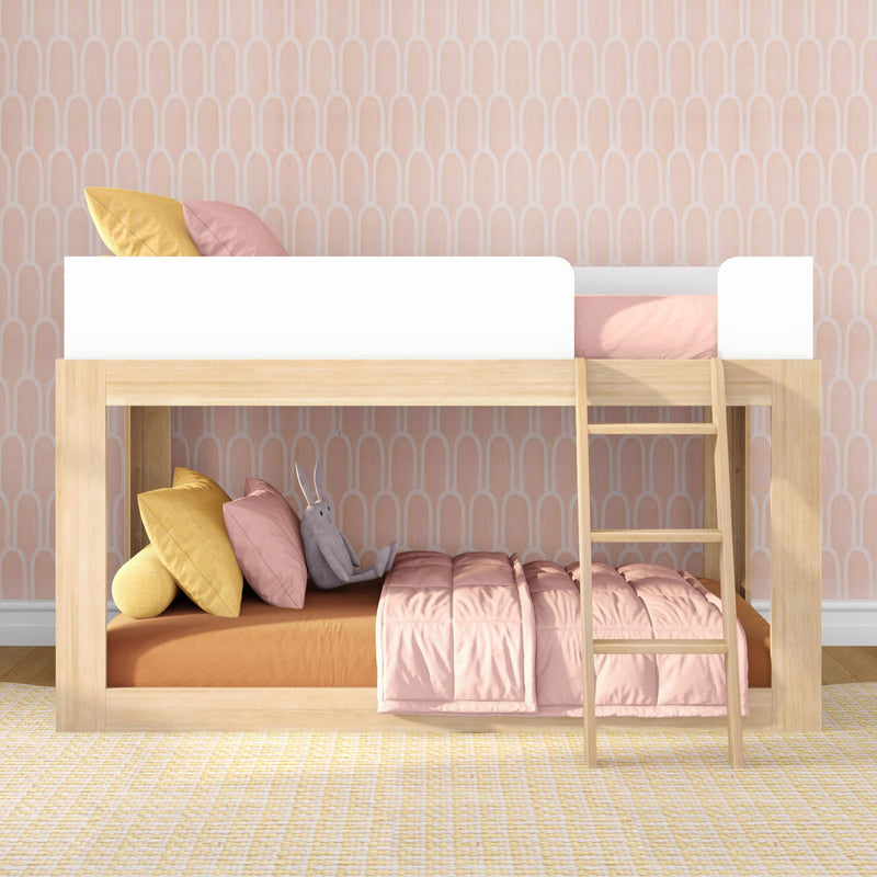 Wooden kids bunk bed with pink patterned wallpaper, pastel bedding, yellow and pink pillows and ladder