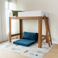 Wooden loft bed with ladder and white safety rail, blue floor cushions and patterned area rug in sunlit modern kids' bedroom with sheer curtains