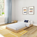 Modern children's bedroom with low wooden platform bed, light blue bedding and curtains, yellow rug, wicker basket and framed abstract art