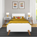 Modern minimalist bedroom interior with white bed frame, mustard quilted duvet and patterned pillow, mid-century bedside tables with yellow lamps, black-and-white striped rug, framed abstract wall art and neutral gray walls illuminated by natural light