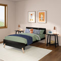 Modern kids bedroom with green bedding, navy striped pillows, plush hippo toy, animal wall art, black bed frame and bedside lamps