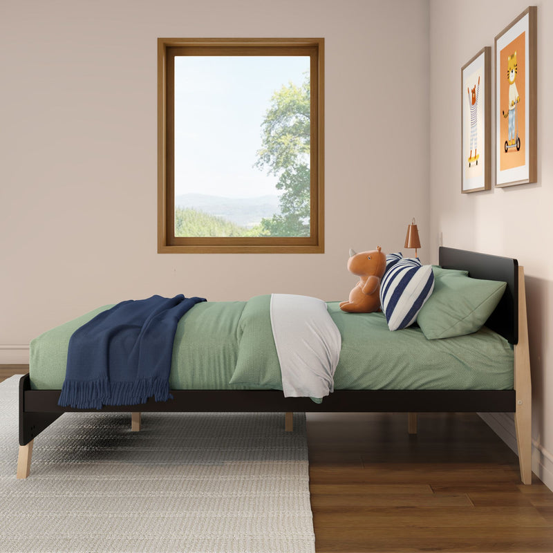Scandinavian kids bedroom with green bedding, navy throw, striped pillow and plush toy on a twin bed, wooden framed window with scenic countryside view and framed animal prints