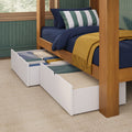 Wooden platform bed with pull-out under-bed storage drawers, navy bedding, green-and-white striped pillow and mustard throw blanket in a cozy bedroom with green textured walls and natural light