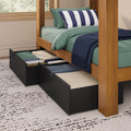 Under-bed storage drawers open beneath a wooden bed with green bedding, navy striped pillow and navy throw blanket in a modern bedroom
