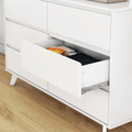 Minimalist white dresser with open drawer showing folded clothes on light hardwood floor, modern bedroom storage and organization
