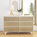 Modern six-drawer white and natural wood dresser with lamp, potted plant, books and abstract art in bright minimalist bedroom