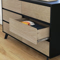 Modern light-wood dresser with black frame and open drawer revealing folded clothes on hardwood floor, stylish bedroom storage furniture