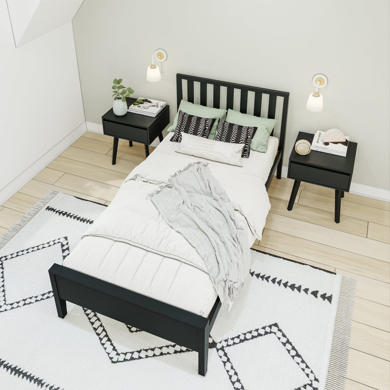 Modern minimalist Scandinavian bedroom with black wooden bed, matching nightstands, wall sconces, soft green pillows and patterned rug on light hardwood floor