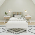 Minimalist Scandinavian bedroom with white platform bed, slatted wood headboard, green accent pillows, matching nightstands, wall sconces and black-and-white patterned rug