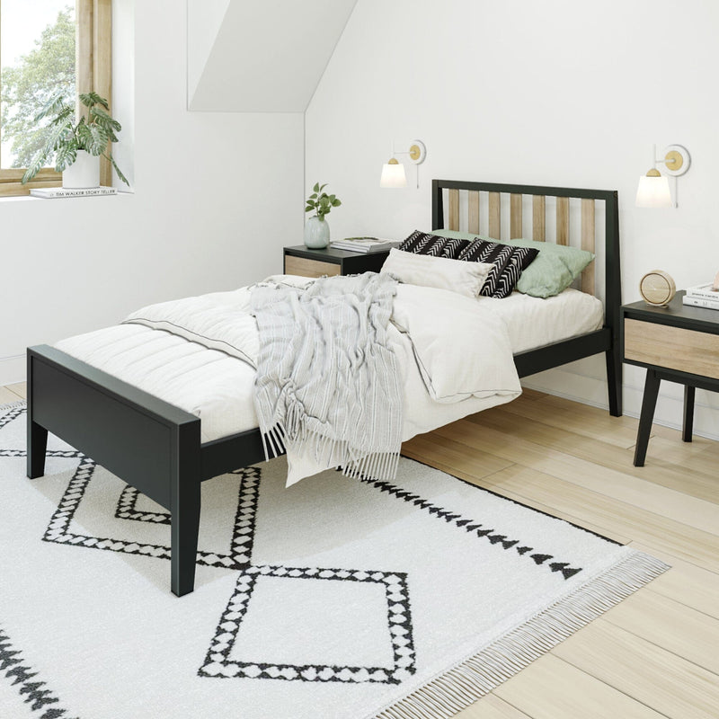 Modern minimalist Scandinavian bedroom with black wooden bed frame, neutral bedding, patterned area rug, wood nightstands, wall sconces and a potted plant by a sunny window