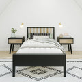 Minimalist modern bedroom with black wood bed frame, light wood headboard, matching nightstands, wall sconces, patterned rug and neutral bedding