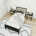 Scandinavian modern bedroom with black wooden bed frame, white bedding, green accent pillows, wood nightstands, geometric rug and wall sconces