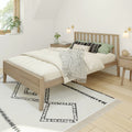 Minimalist Scandinavian bedroom with light wood platform bed, neutral bedding, green accent pillows, black-and-white geometric rug and bedside tables