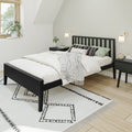 Minimalist modern bedroom with black slatted bed frame, white bedding, patterned pillows, mint throw, geometric area rug, wooden floor and wall sconces