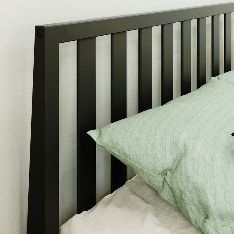 Modern black metal slatted headboard with pale green pillow and beige linen bedding against a white bedroom wall