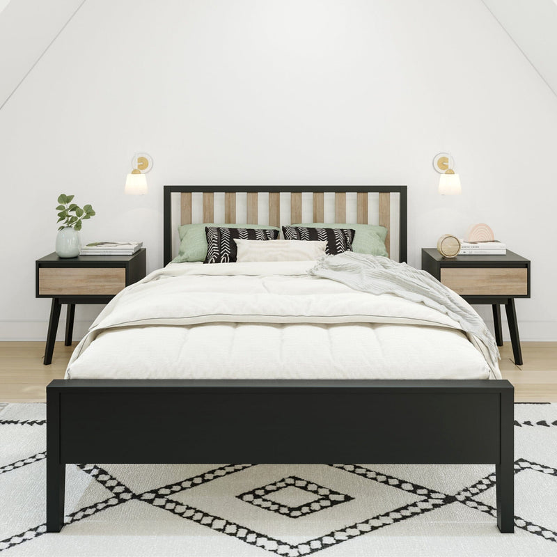 Minimal Scandinavian bedroom interior with black wood bed frame, white bedding, green and patterned pillows, matching nightstands, wall sconces, potted plant and geometric rug