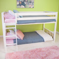 White wooden bunk bed with blue quilt, pink pillows and pink shag rug against a green accent wall in a kids bedroom