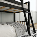 Black metal loft bed frame with ladder, wooden slats and mattress, striped gray throw over white bedding in a modern minimalist bedroom interior