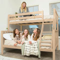 Four smiling girls on a natural wood bunk bed in a bright modern kids' bedroom with cozy neutral bedding and ladder