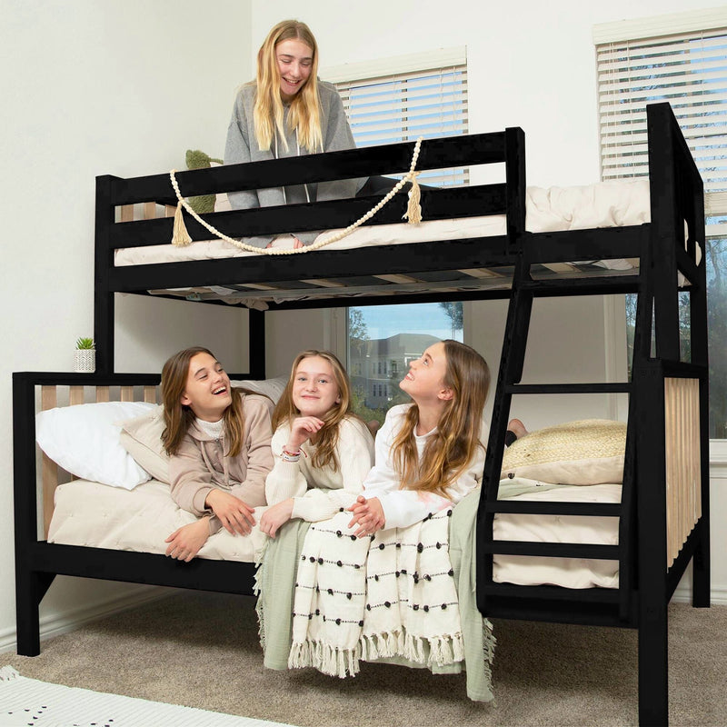 Four smiling girls sitting on a black wooden bunk bed with ladder and decorative bead garland, cozy neutral bedding in a bright modern bedroom