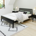 Modern minimalist bedroom with black slatted bed, white bedding, green accent pillows, geometric rug and wood nightstand