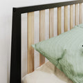 Modern black metal frame bed headboard with vertical light wood slats and green linen pillow on beige bedding