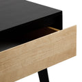 Minimalist mid-century modern desk with black top and natural wood drawer front partially open, showing interior storage space