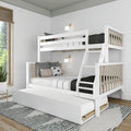 White wooden bunk bed with ladder and pull-out trundle, black-and-white bedding in a modern Scandinavian kids' bedroom with wall sconces and natural wood accents