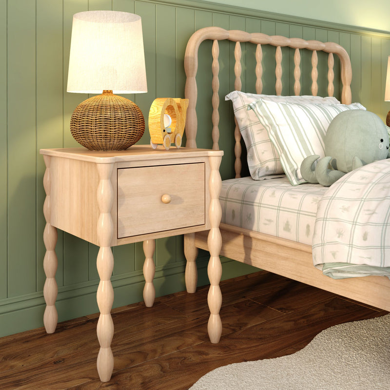Children’s bedroom with light wood spindle bed and matching nightstand, rattan table lamp, wooden toy, striped pastel bedding, plush octopus and hardwood floor