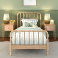 Children's bedroom with light wood spindle bed, green paneled wall, striped bedding, plush octopus, nightstands with rattan lamps