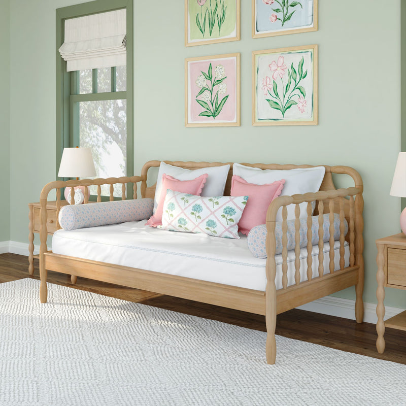 Pastel nursery with wooden daybed, pink pillows and floral framed art on mint green walls, cozy children's bedroom decor