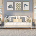Coastal bedroom decor: white daybed with quilted cover, blue-striped and textured pillows, and framed nautical prints on a blue-gray wall